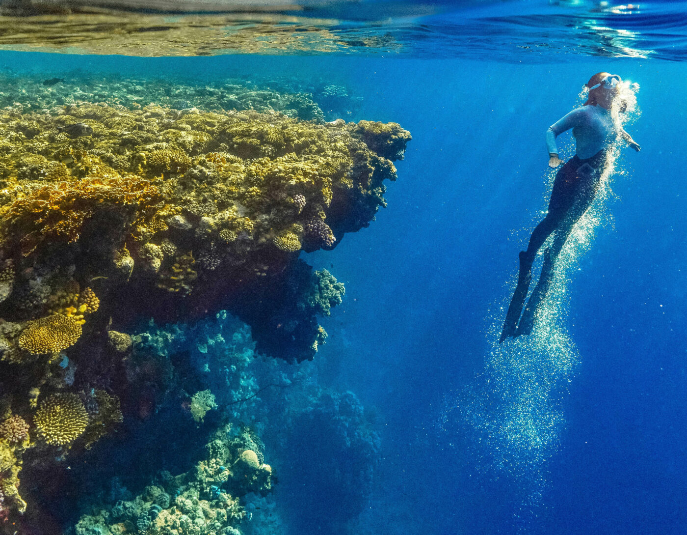 Woman free diving in the crystal-clear waters of Raja Ampat