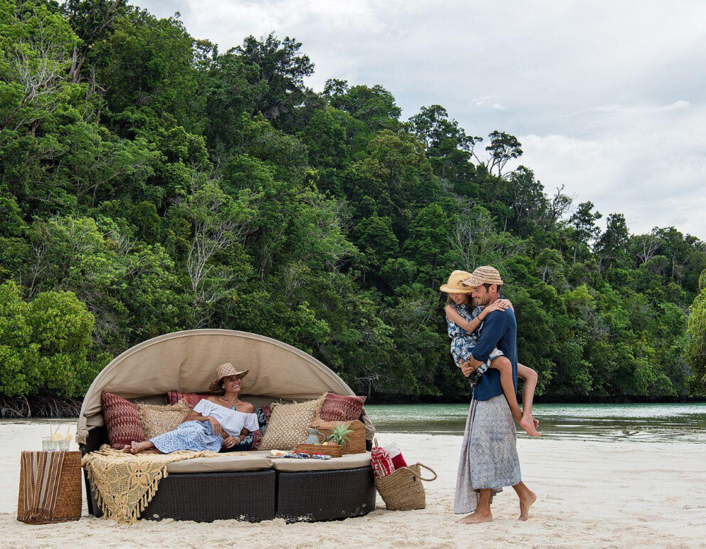 Family relaxing on a pristine beach near Sorong, Indonesia.