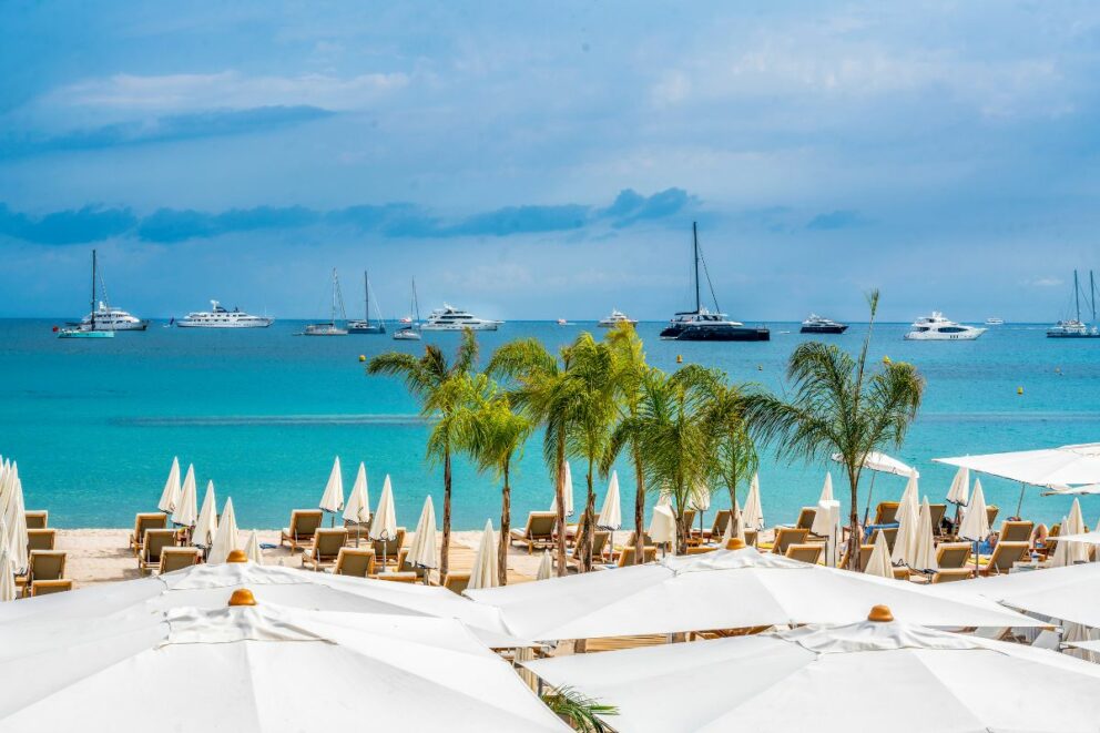 Beach club in Cannes, some catamarans and yachts are anchored in front of the beach