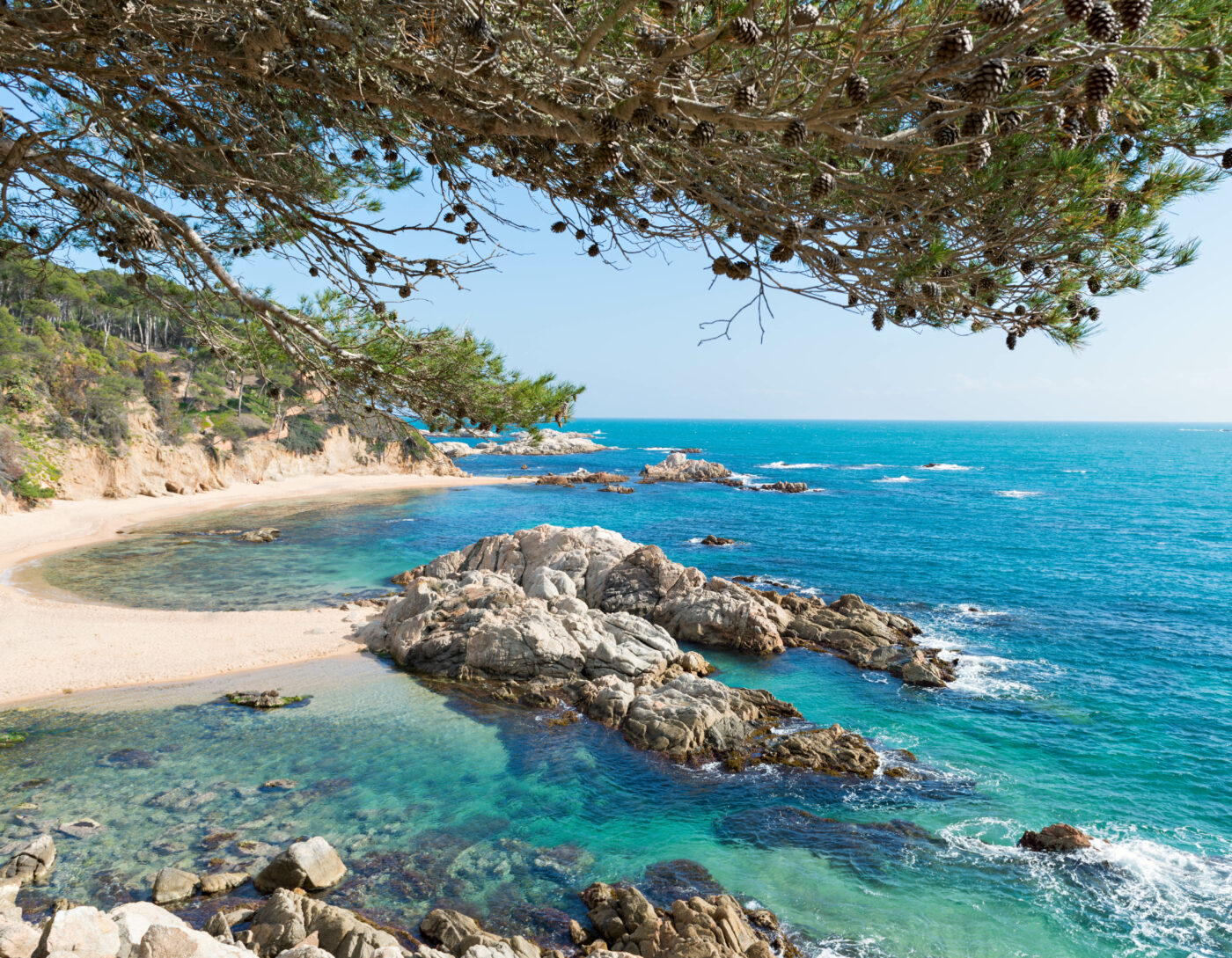 Turquoise cove on the Costa Brava, Spain — a luxury yacht destination with pine-covered cliffs and crystal-clear Mediterranean waters