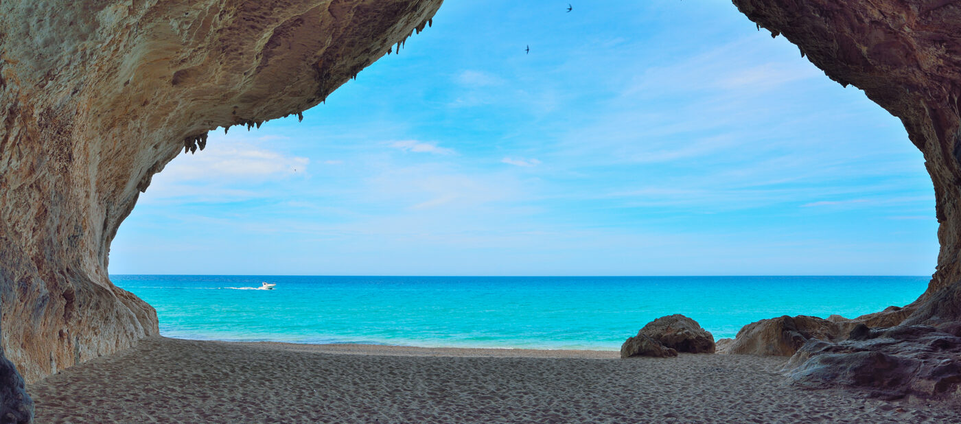 motorboat passing by a big cave in Cala Luna, Sardinia