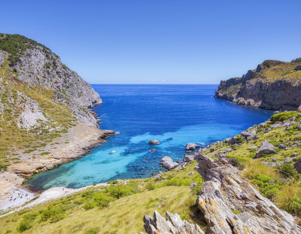 ort de Pollença cove with boats anchored in calm water.