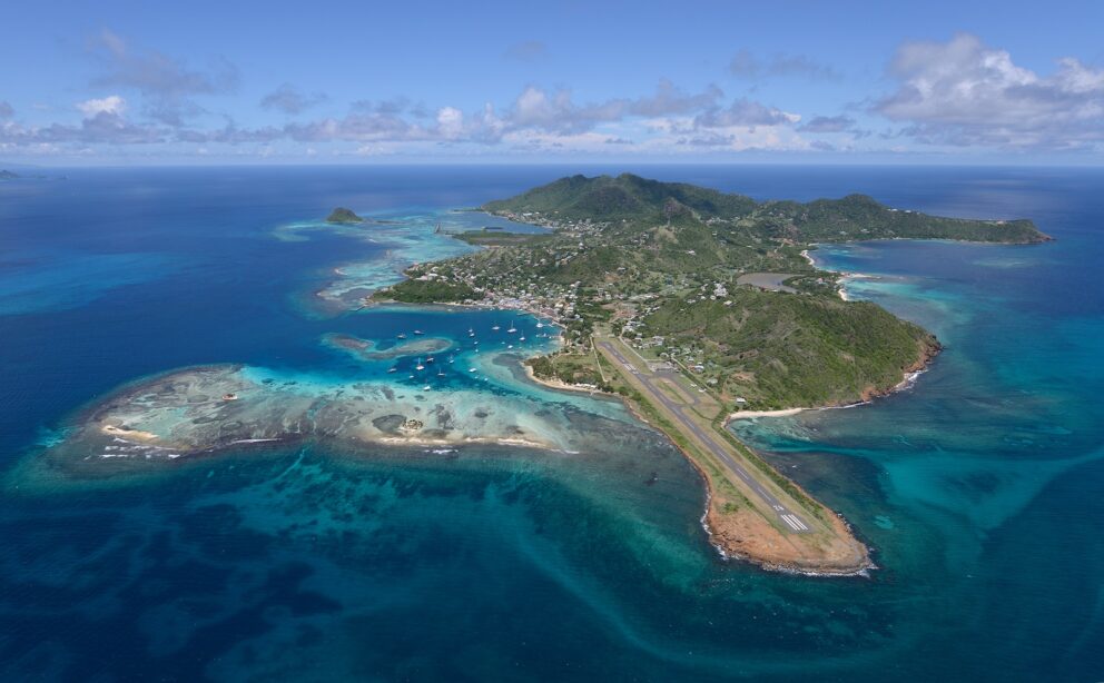 Aerial view of Union Island showing the airport runway, town, and surrounding Caribbean Sea.