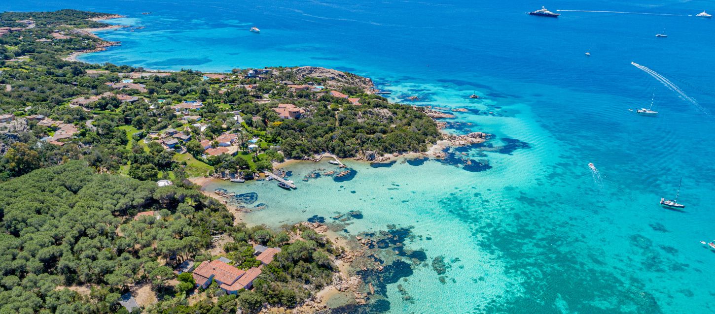 Vista aérea de la costa de Cerdeña, agua turquesa y barcos navegando a lo lejos
