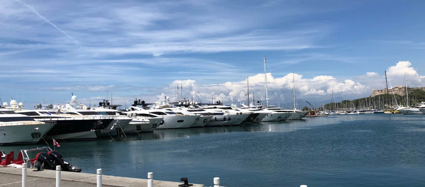 French Mediterranean port with a selection of luxury yachts moored in a row under a blue sky