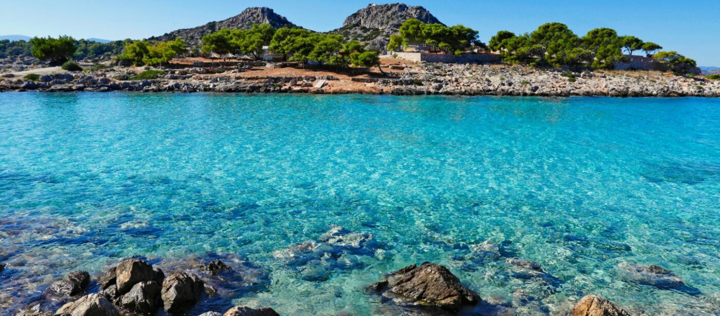A scenic view of the clear, turquoise waters at Aponisos beach, located near Agistri Island, Greece.