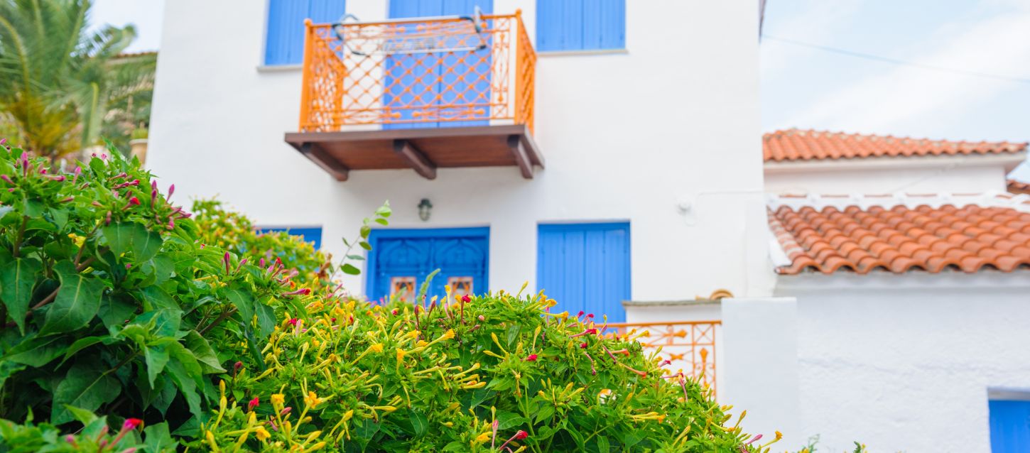 The image displays a traditional Greek-style building, possibly named Villa Ourania, in Skopelos.