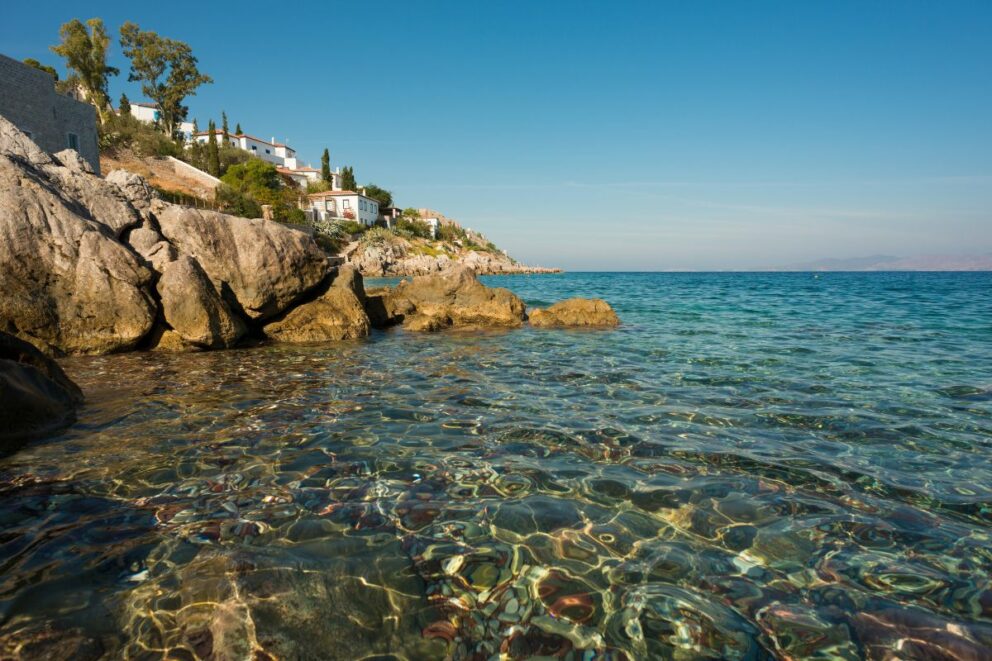 A scenic view from a hill overlooking a large body of blue water with several small islands in the distance and tree branches framing the shot.