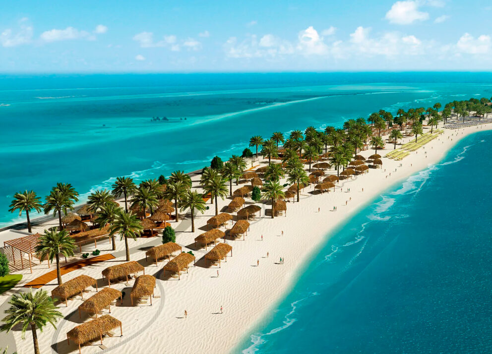 Aerial view of Sir Bani Yas Island in Abu Dhabi showing a pristine white sandy beach lined with palm trees and thatched cabanas beside turquoise blue waters under a bright sky.
